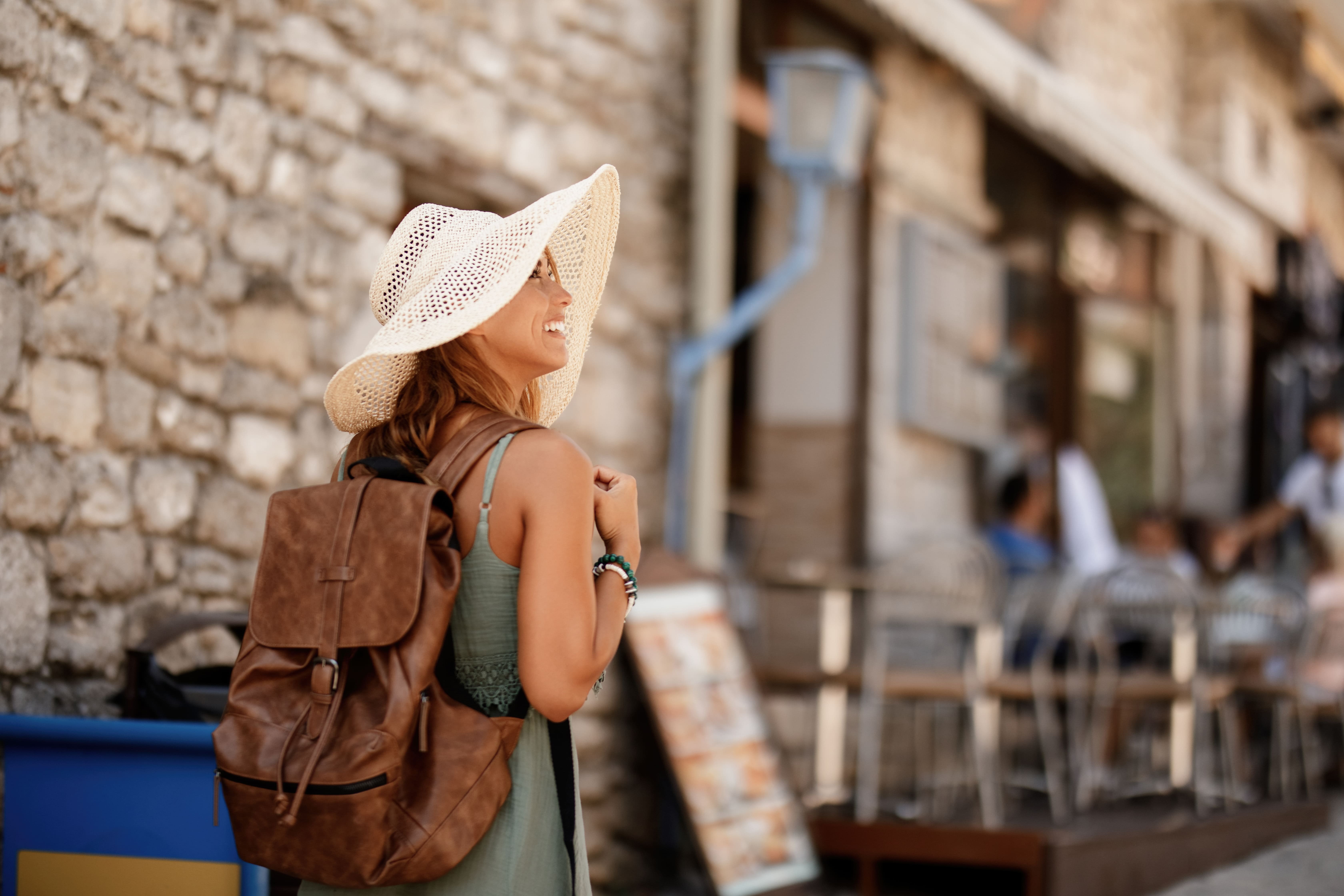 happy-female-tourist-with-back-back-taking-walk-exploring-town-summer-vacation (1)